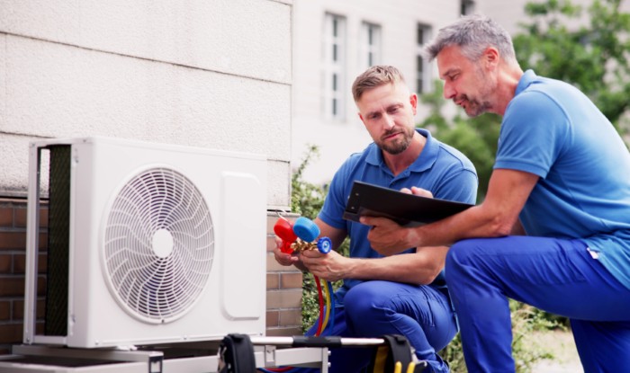 HVAC technicians reviewing an outdoor air conditioning unit in Greeley, CO
