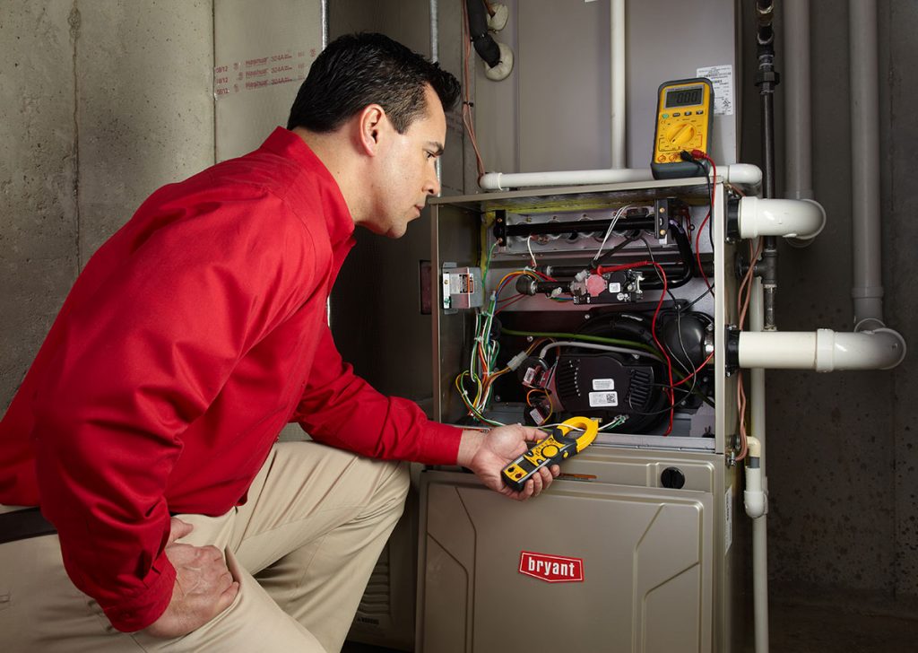 Heating and air conditioning technician servicing an indoor furnace in Greeley, CO