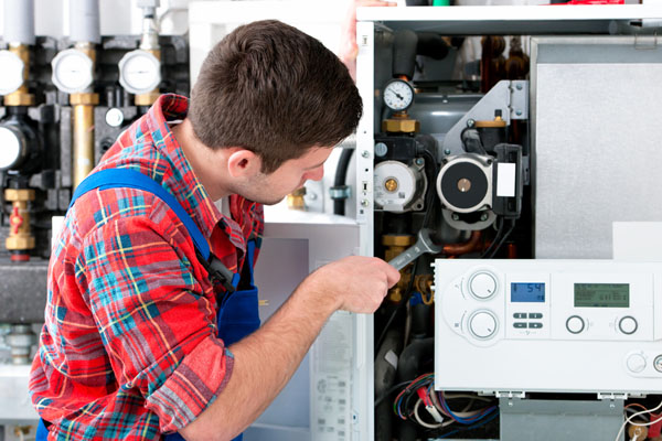 HVAC technician inspecting and repairing boiler controls in Greeley