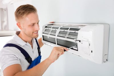 HVAC technician cleaning and repairing a ductless mini split AC in Greeley, CO