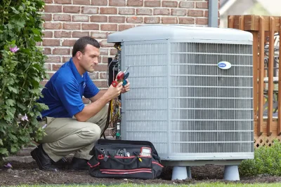 HVAC technician inspecting an outdoor air conditioning unit in Greeley, CO
